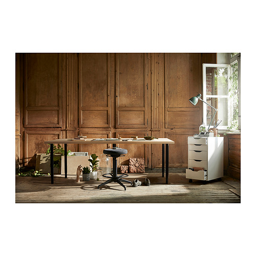 Configuración de oficina con escritorio, unidad de almacenamiento y taburete LAGKAPTEN. Paredes de paneles de madera, luz natural de ventanas, plantas y decoración minimalista.