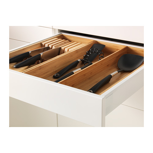 Cajón de cocina blanco abierto con divisor de madera que sostiene cuchillos, tijeras y espátula de mango negro.