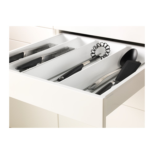 Abra el cajón de la cocina con organizadores, cuchillos, utensilios y un batidor.