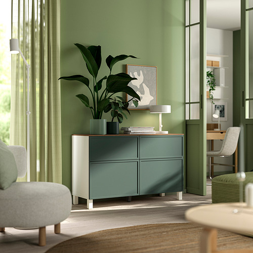 Sala de estar moderna con aparador BESTÅ , plantas, lámpara, libros y arte. Diseño blanco y verde, ligero y aireado.