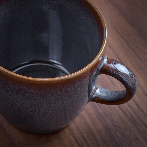 Taza artesanal con acabado rústico y brillante sobre mesa de madera.