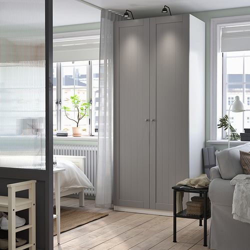 Dormitorio moderno con armario alto PAX gris, escritorio y sofá gris.