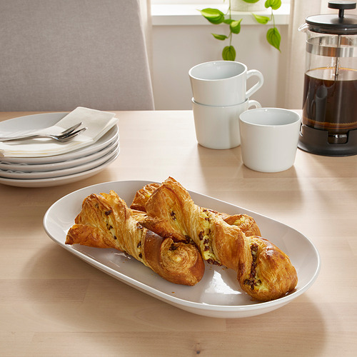 Pasteles de color marrón dorado en mesa de madera con platos, tazas y prensa francesa.