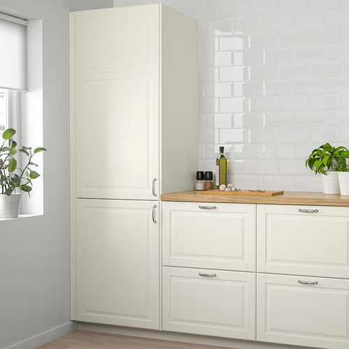 Mueble de cocina BODBYN blanco roto con paneles biselados contra la pared de azulejos; Armarios con tiradores de plata debajo de la encimera de madera.