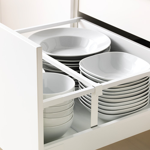 Organizador de cajones de cocina con divisores ajustables que sostienen pilas de platos y tazones blancos.