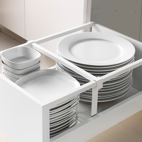 El cajón abierto de la cocina revela platos blancos organizados: platos, tazones y tazas en un moderno gabinete blanco.