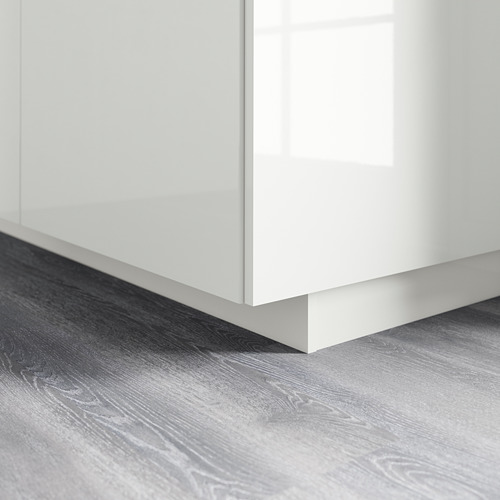 Zócalo de armario de cocina blanco brillante sobre suelo de madera.