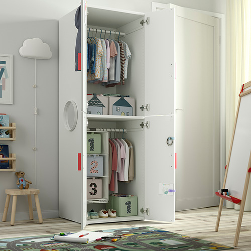 Habitación de niños con armario blanco abierto, ropa en perchas, estanterías con papeleras y juguetes.
