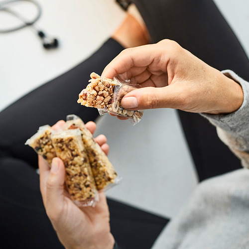 Sosteniendo barras de cereales con nueces y semillas, listas para comer.
