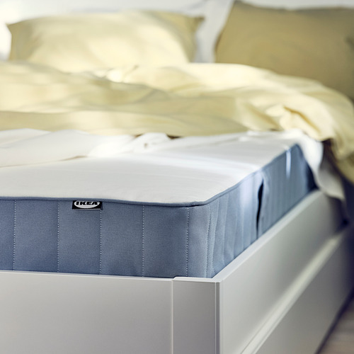 IKEA VESTMARKA colchón sobre cama blanco, bordes azul claro, diseño sencillo.