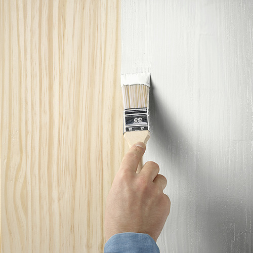 Una mano usa un pincel para pintar una superficie de madera con TRIXIG, una pintura semimate para muebles de interior a base de agua.