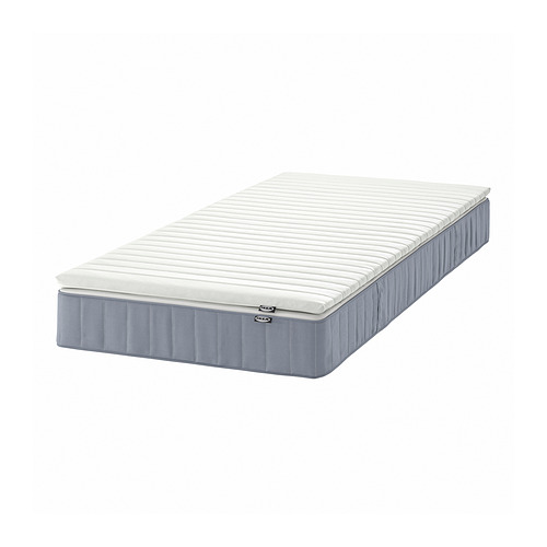 Es un colchón VESTERÖY de IKEA gris claro con una tapa blanca, rectangular y texturizada para mayor comodidad.