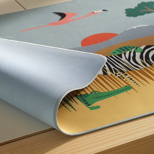 Almohadilla de escritorio con estampado de temática sabana, enrollada sobre un suelo de madera.