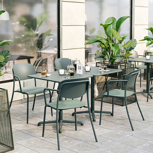 Conjunto de muebles de exterior verdes con sillas acolchadas y mesa pequeña, ubicado en un patio de baldosas con plantas.
