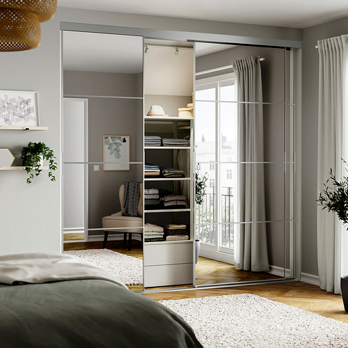 Dormitorio moderno con puertas de armario con espejos, cama cabecera verde y grandes ventanales con cortinas grises.