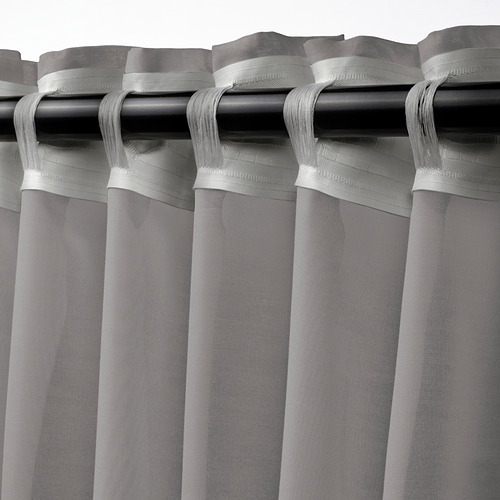 Las cortinas grises transparentes cuelgan de las varillas, difundiendo la luz del sol, brindando privacidad con un aspecto elegante y casual.