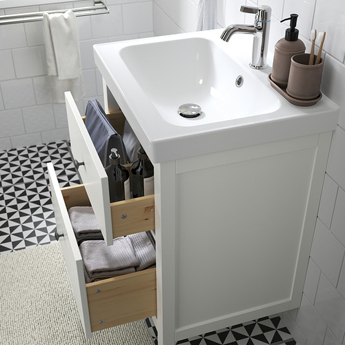 Moderno mueble de baño con cajón que muestra toallas y artículos de tocador, encimera blanca y grifería cromada.