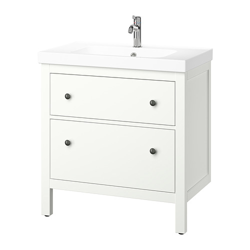 Un tocador de baño blanco HEMNES con dos cajones y un lavabo de cerámica. Tiene pomos negros y un grifo cromado.