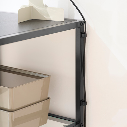 Escritorio con tapa de cristal y estructura metálica. Dos compartimentos de almacenamiento de color beige. Las pinzas para cables gestionan los cables.