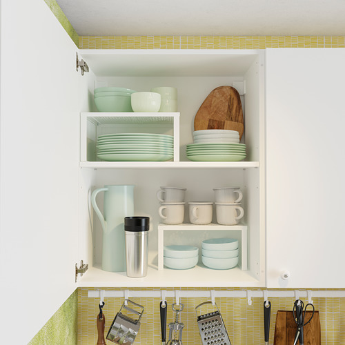 Mueble de cocina KNOXHULT, blanco, organizado con platos verdes, tazas y tablas de madera, cuidadosamente guardado, diseño moderno.