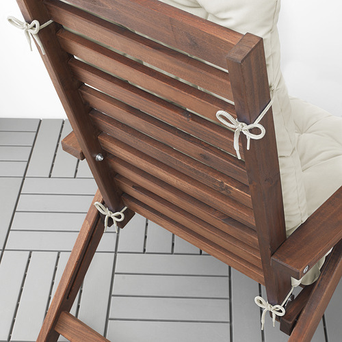 Silla de madera con cojín beige, asegurada por lazos. Ideal para uso en exteriores.