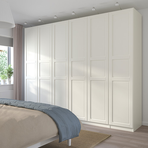 Armario PAX blanco con múltiples compartimentos junto a la cama.