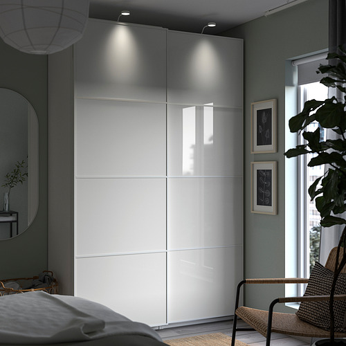 Dormitorio moderno con armario blanco PAX, puertas de vidrio e iluminación ambiental.