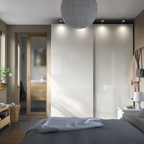 Dormitorio moderno con armarios PAX, puertas corredizas, cama gris e iluminación tenue.