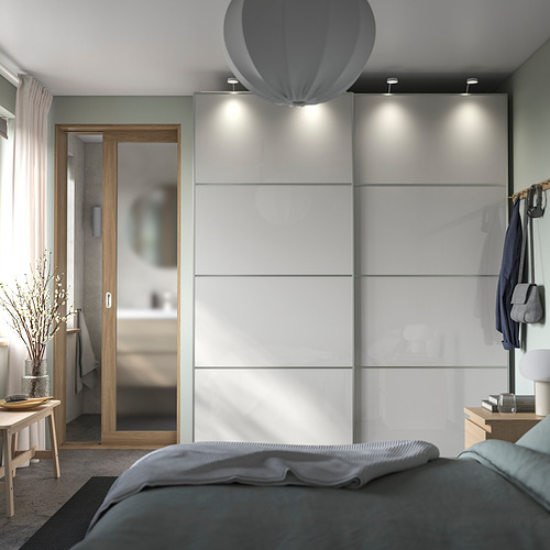 Esta imagen muestra un dormitorio moderno con un armario corredero blanco de alto brillo HOKKSUND, iluminación superior y decoración.