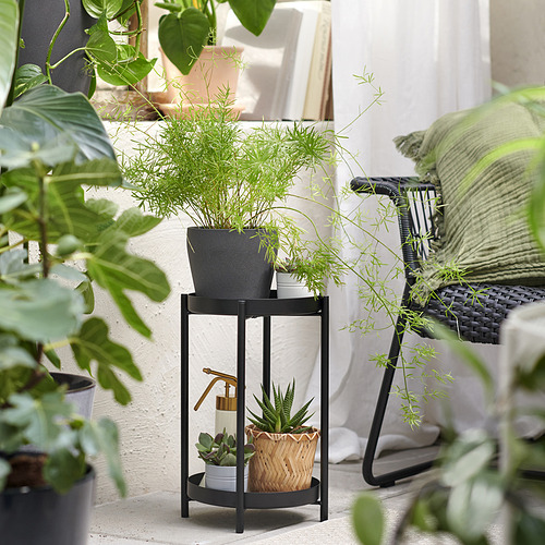Soporte de plantas OLIVBLAD negro con múltiples plantas en macetas de diferentes tamaños y formas. Estructura metálica, uso interior/exterior.