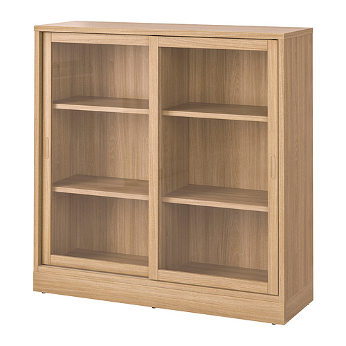 Un mueble de madera TONSTAD en color roble. Tiene puertas correderas de vidrio, tres estantes y un diseño clásico.