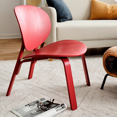 Silla elegante de color rojo brillante cerca del sofá crema, diseño minimalista moderno, marco de madera.
