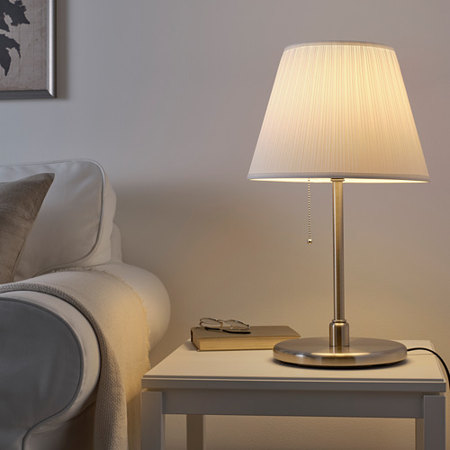 Lámpara MYRHULT con pantalla crema junto a silla gris.