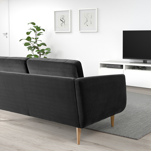 Sala de estar moderna con sofá de terciopelo negro, patas de madera, planta, arte de pared, tv y alfombra gris.