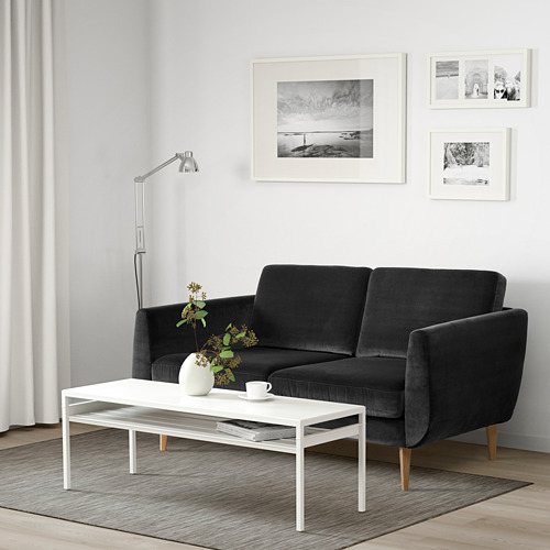 Sala de estar moderna con sofá de terciopelo gris oscuro, mesa de centro blanca y arte de pared en blanco y negro.