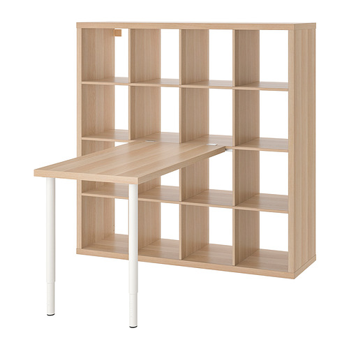 Mueble de escritorio KALLAX de madera clara con estantes, patas blancas y tapa en ángulo.