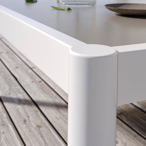 Una mesa de exterior blanca y moderna con patas cilíndricas. Fabricado en aluminio y acero con recubrimiento en polvo, perfectamente adaptado para terrazas.