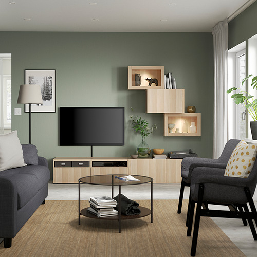 Sala de estar moderna con sofá gris, sillón, mesa de café y mueble de televisión. Tv de pantalla plana en pared verde con arte y plantas.