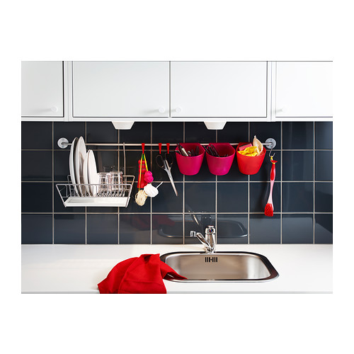 Fregadero de cocina moderno en acero inoxidable, con utensilios para colgar, tazas y toallas rojas en la pared de azulejos azul oscuro.