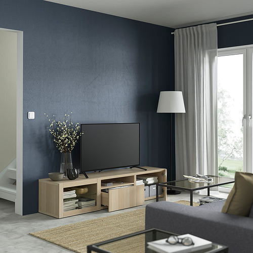 Banco de tv de roble con cajones, TV de pantalla plana, jarrón negro con flores, alfombra gris, gestión de cables.