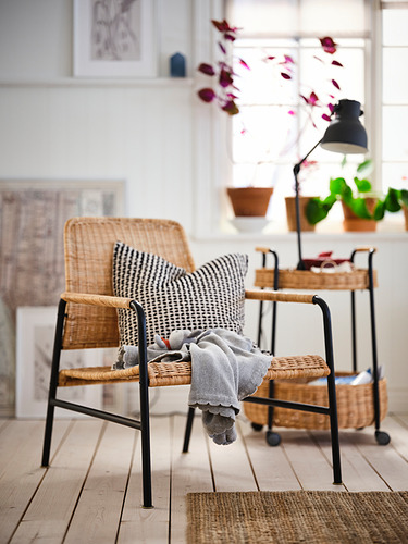 Silla de mimbre ULRIKSBERG en acogedora habitación con manta y plantas.