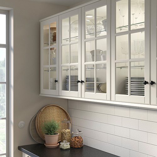 Cocina moderna con gabinetes BODBYN de vidrio blanco, elegante y reflectante, que alberga platos apilados. Tamaño: alto, más ancho que los artículos de decoración del mostrador.