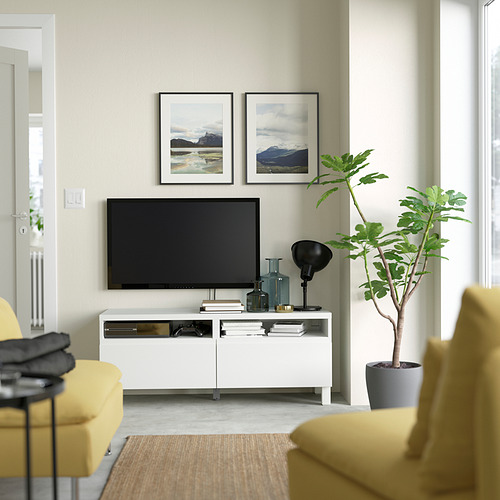 Sala de estar moderna con tv, banco BESTÅ, sofá amarillo, planta, arte de montaña.