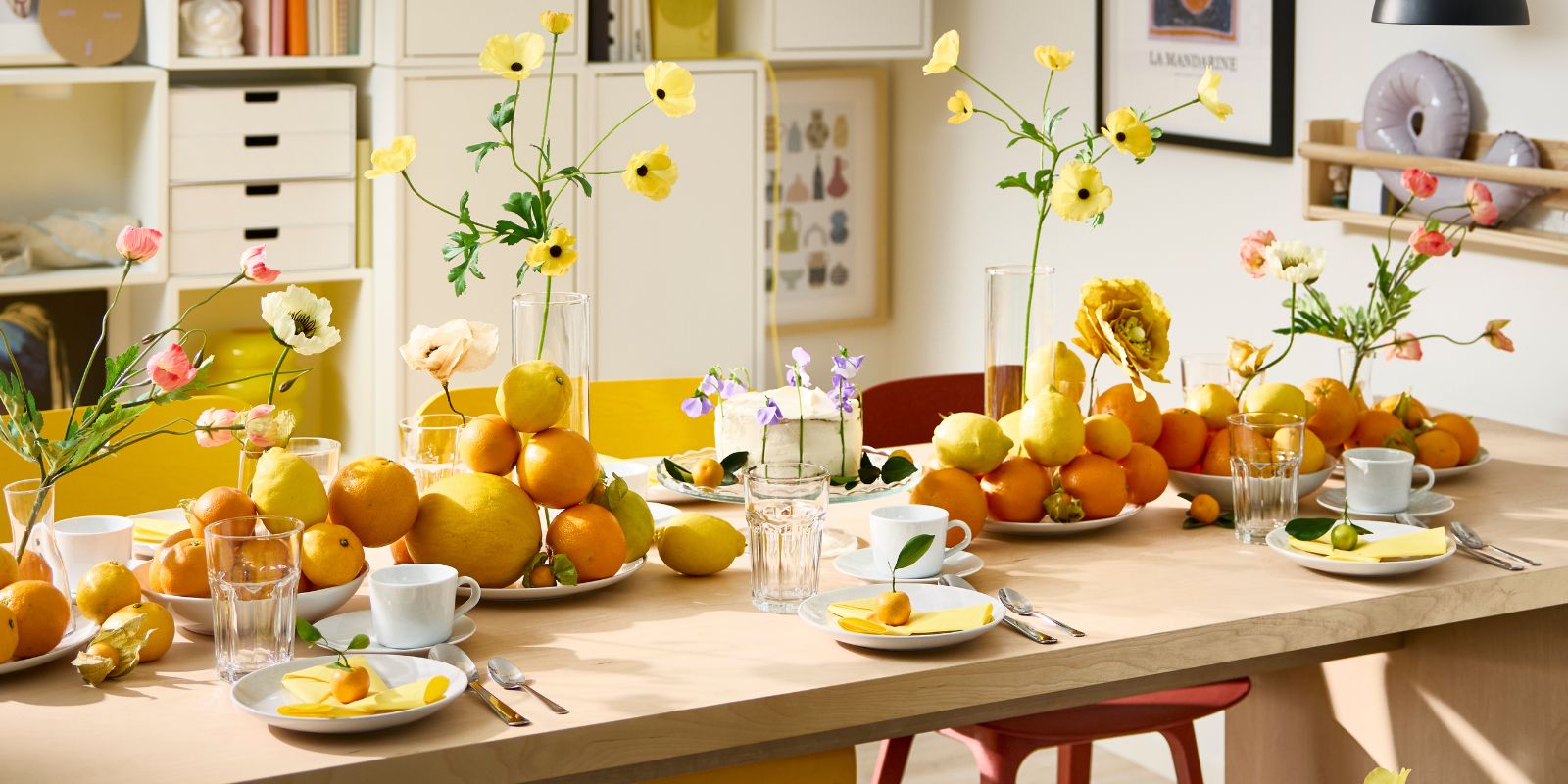A BERGSHYTTAN table has a table setting with white plates and POKAL glasses and decorative oranges and lemons on plates.