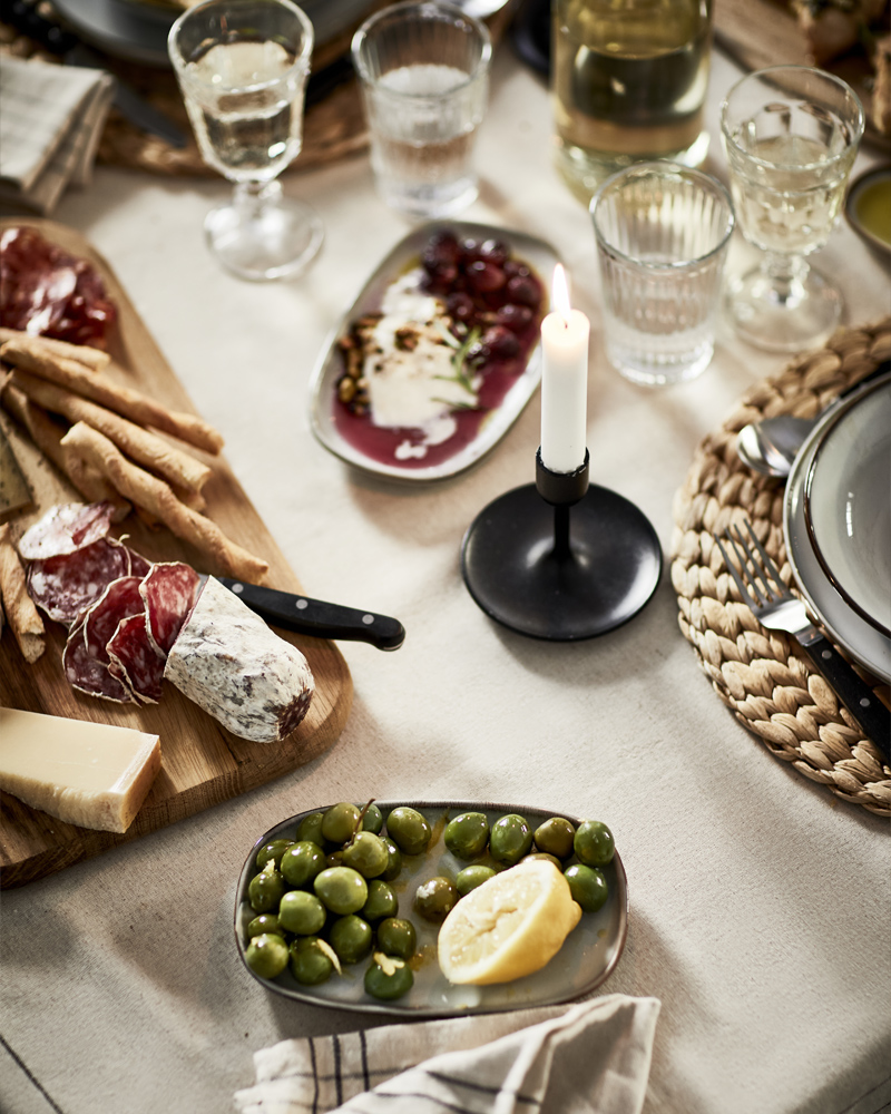 Elegant table with olives, cheese, charcuterie, and wine glasses – cozy Scandinavian dining setup.