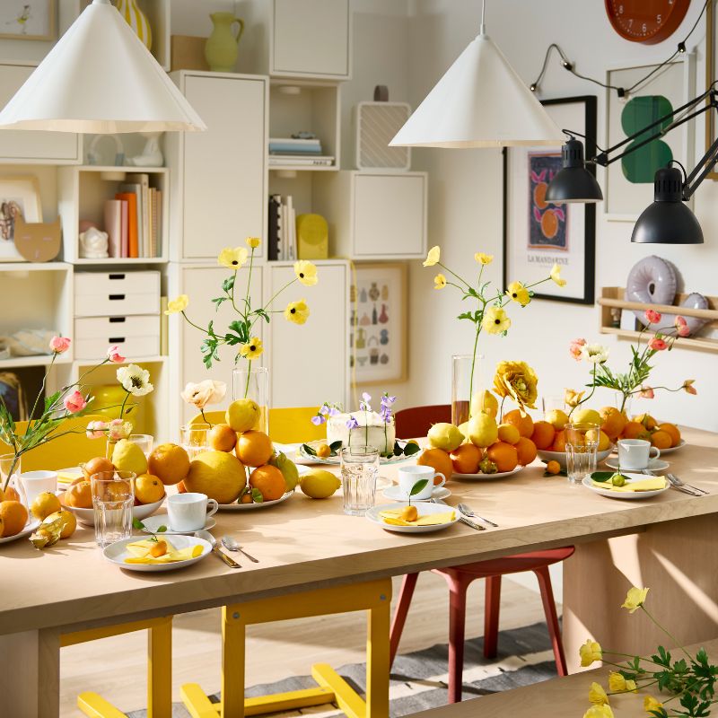 A BERGSHYTTAN table has a table setting with white plates and POKAL glasses and decorative oranges and lemons on plates.