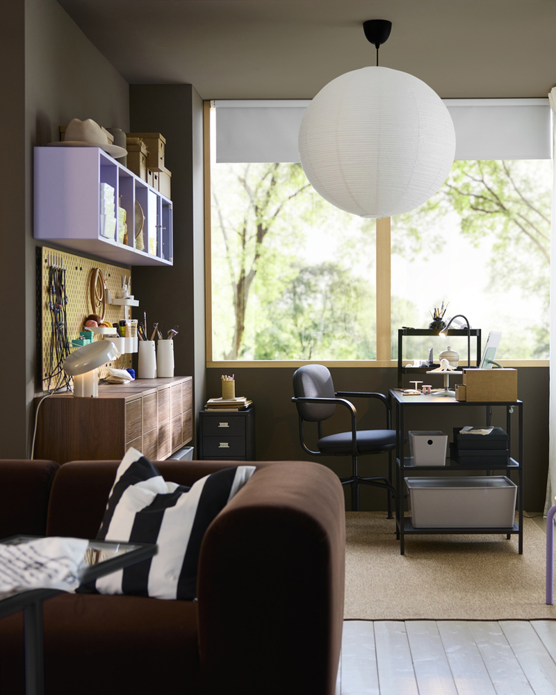 A shared dedicated workspace setup with a blackbrown VITTSJÖ desk featuring a glass top, a chair, storage boxes, and a lamp.