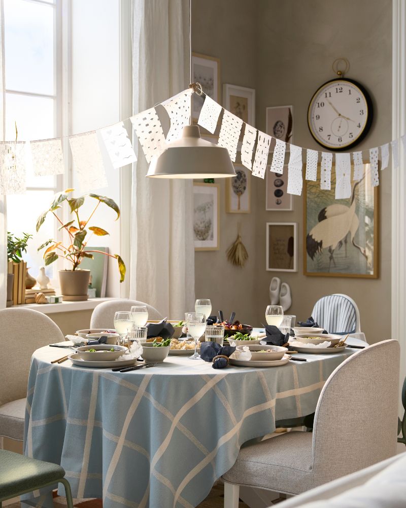 A bright dining room has a ROSENTORP extendable table that has been pulled out to accommodate five chairs and one highchair