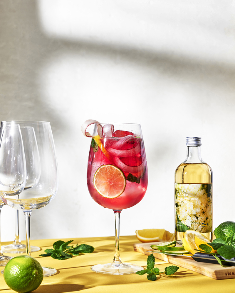 Refreshing summer drink with lime, mint, and elderflower on a vibrant yellow table.