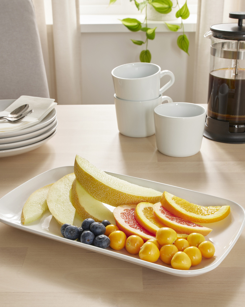 Fresh fruit platter with melon, citrus, blueberries, and yellow cherries on a breakfast table.